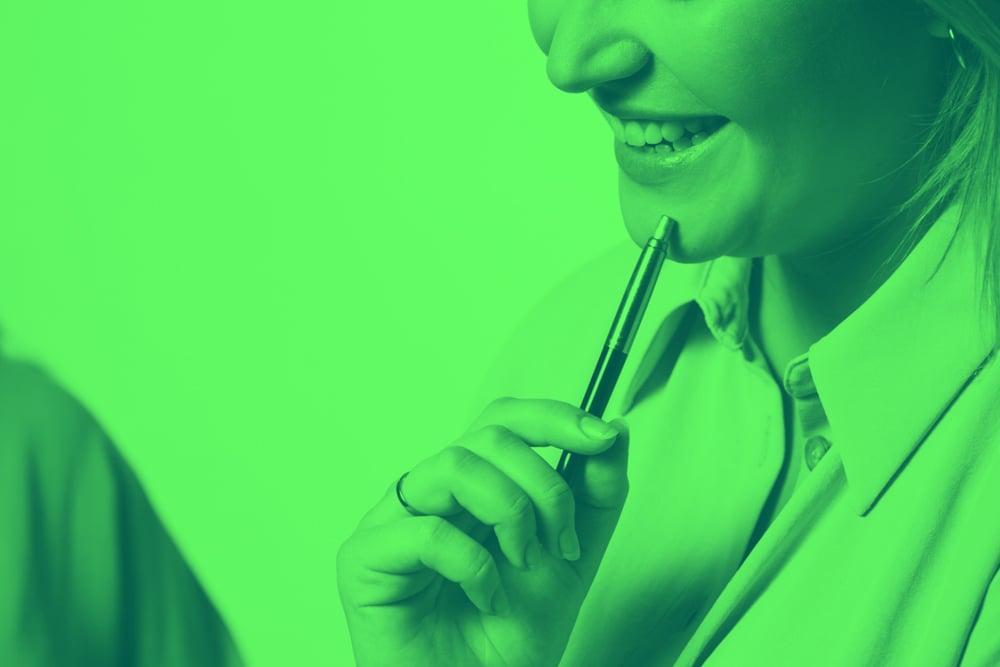 Smiling professional holding a pen during a coaching session, symbolising leadership development and behavioural change.