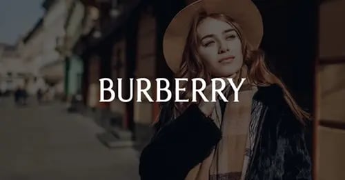 Photo of a woman stylishly dressed and standing on a city street with a white version of the Burberry logo superimposed in the middle foreground