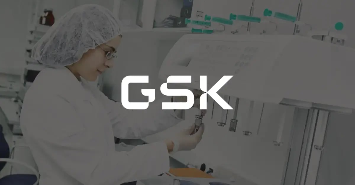 Photo of a woman in a lab coat and protective equipment holding a vile up to a digital machine and a white version of the GSK logo superimposed in the middle foreground