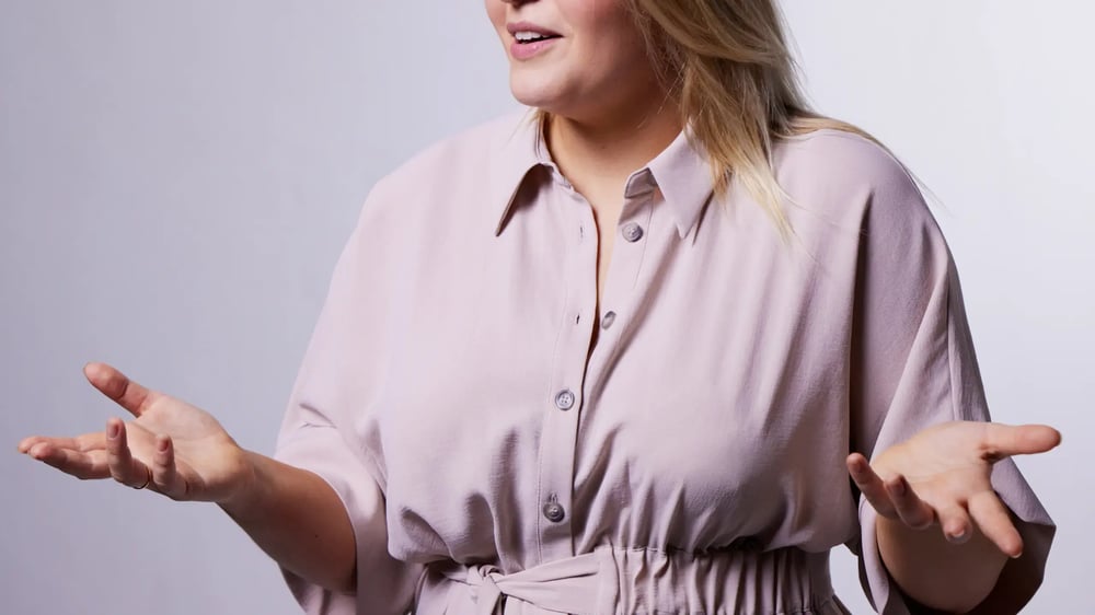Woman speaking in a purple dress in a presentation or facilitation setting.
