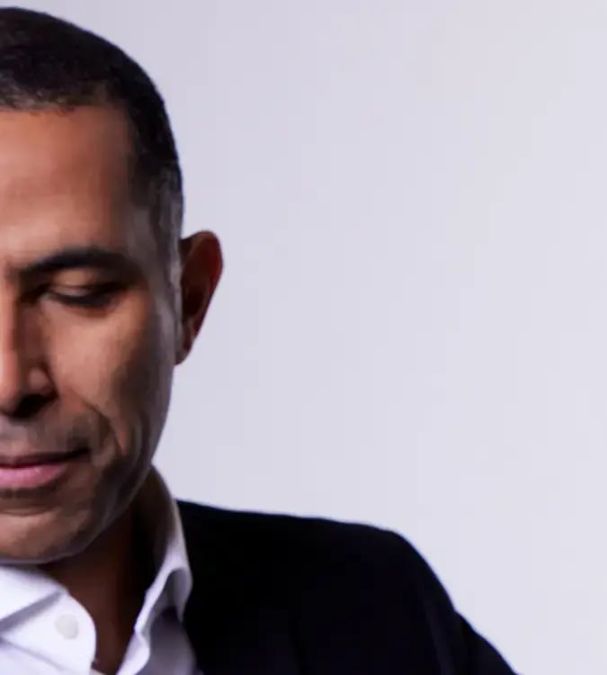 Close-up photo of a man in a dark jacket with his eyes closed