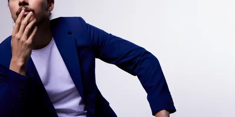 Man leaning to one side with a casual stance indoors.