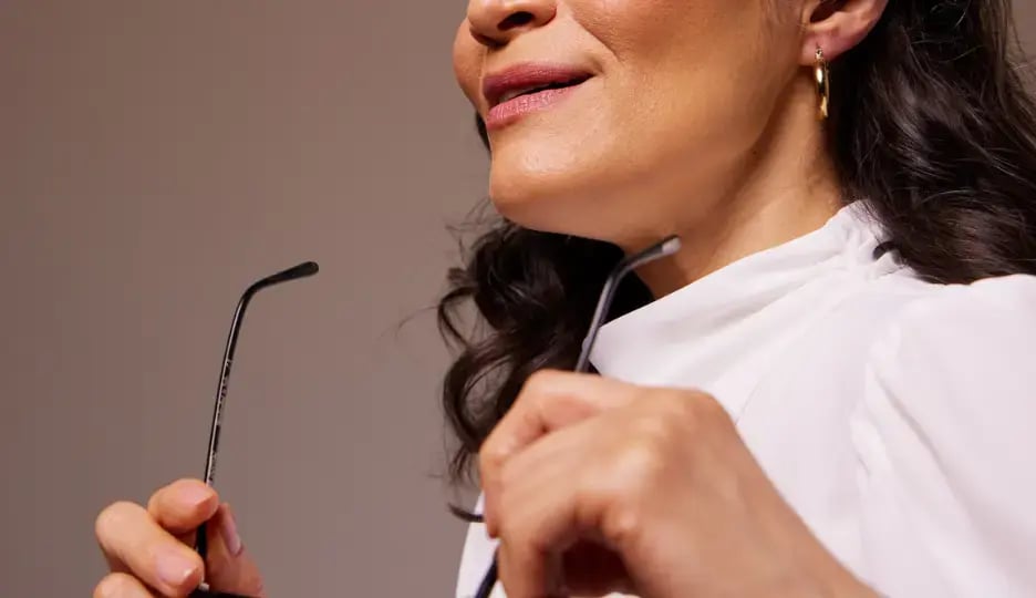 Photo of a woman in a white blouse holding a pair of eyeglasses