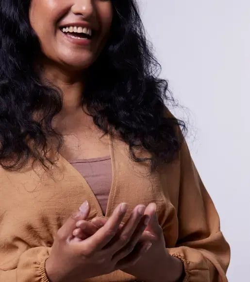 A photo of a woman with dark hair and wearing a brown dress smiling