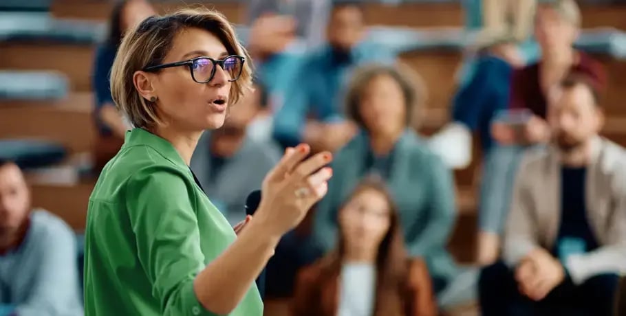Photo of a woman in a green shirt giving a talk or lecture to a group