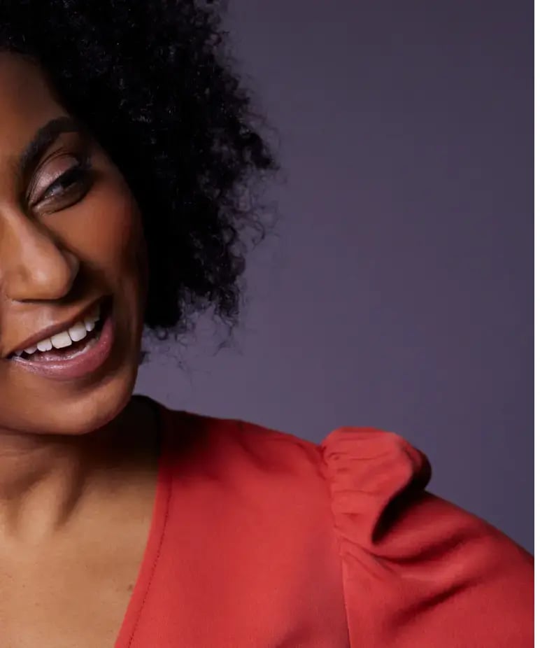Photo of a black woman smiling and wearing a red dress
